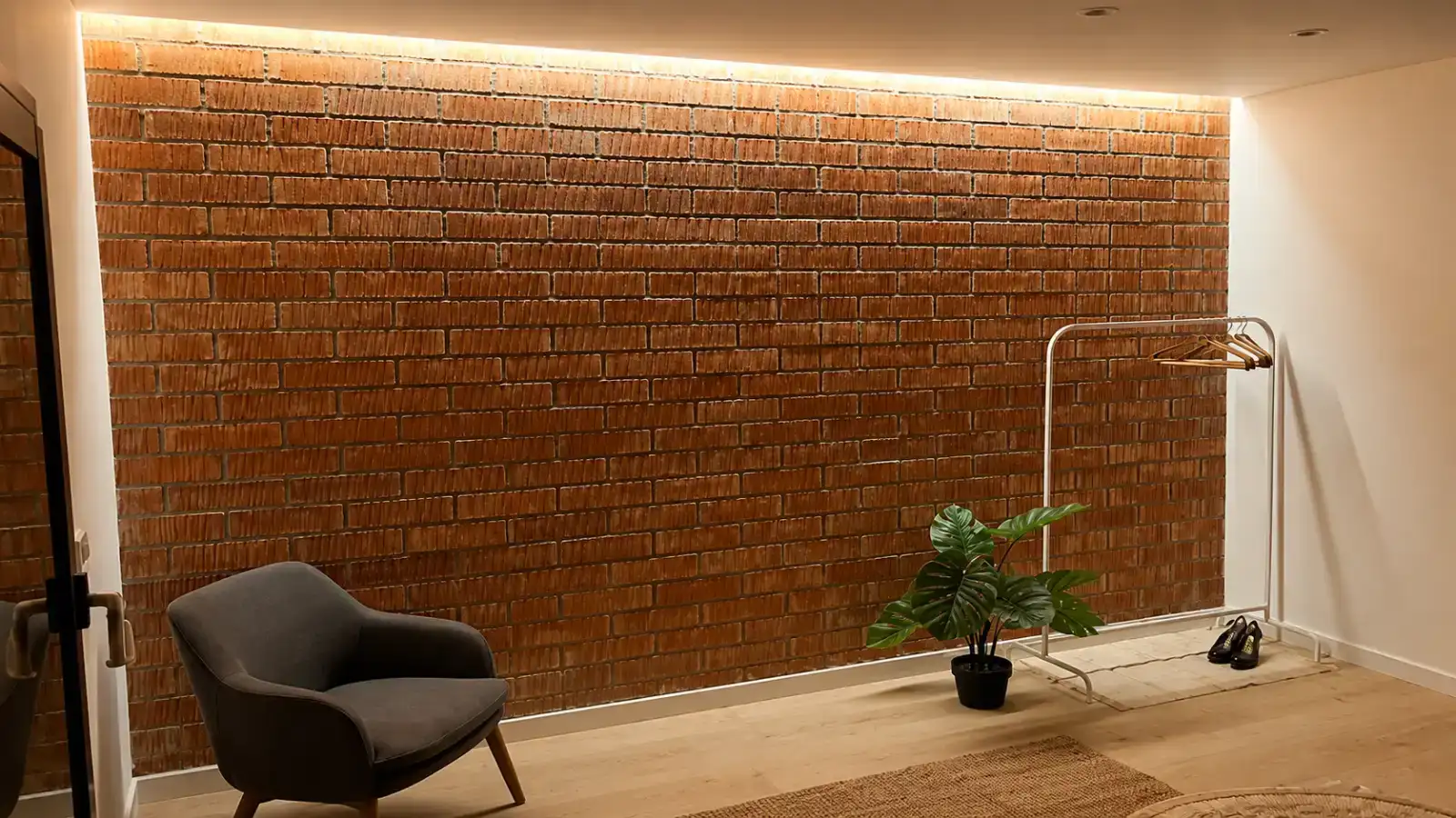 Reforma de vivienda con pared de ladrillo visto iluminada por foseado LED superior en Barcelona